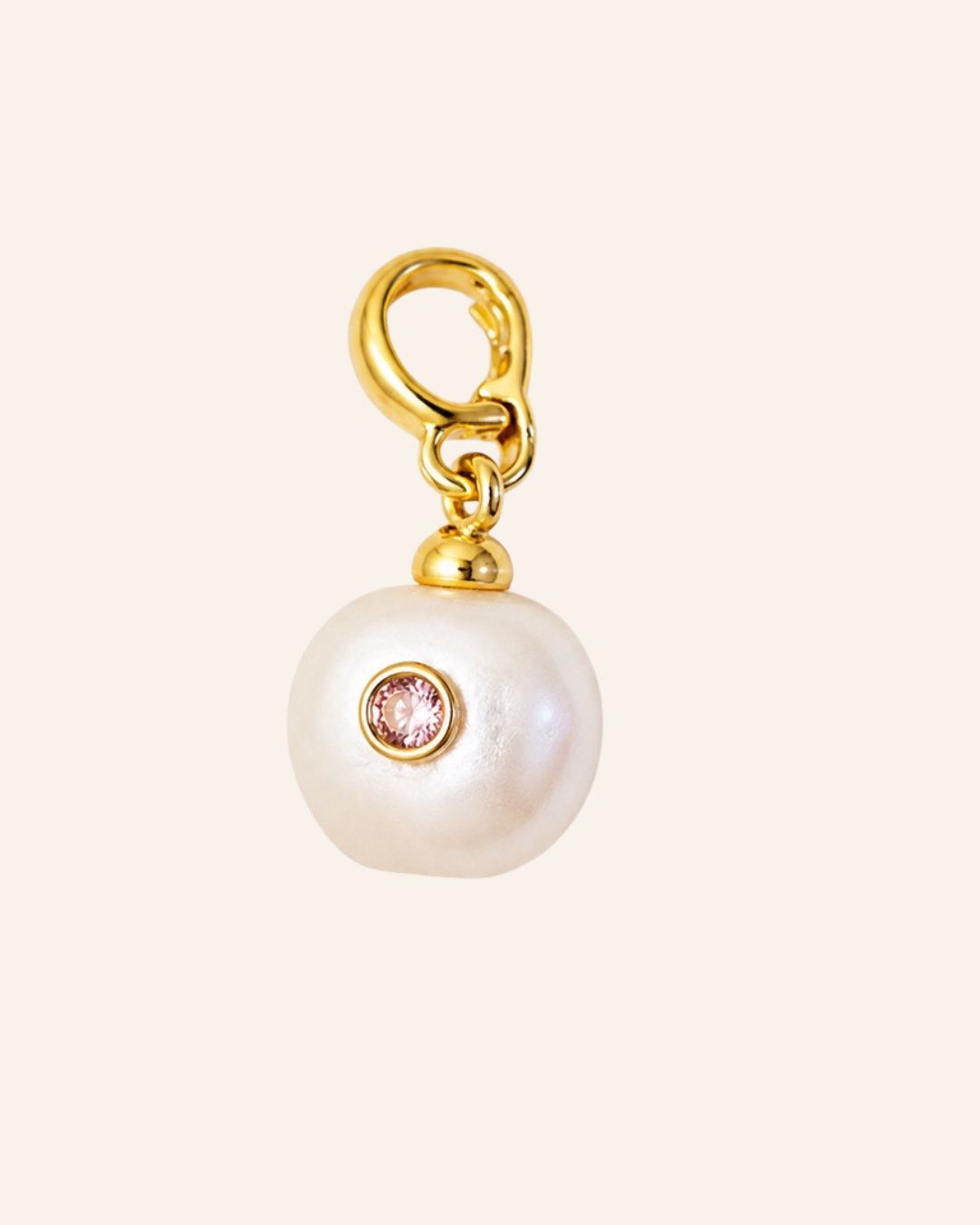 A gold charm featuring a large, irregular white pearl with a small round moissantite gemstone inset, suspended from a gold lobster clasp, shown against a solid pale pink background.
