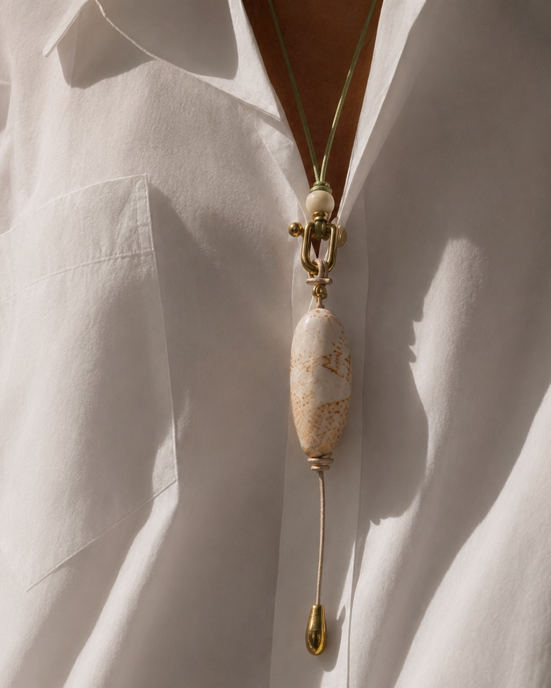 Necklace with a large bead and gold chain on a white shirt