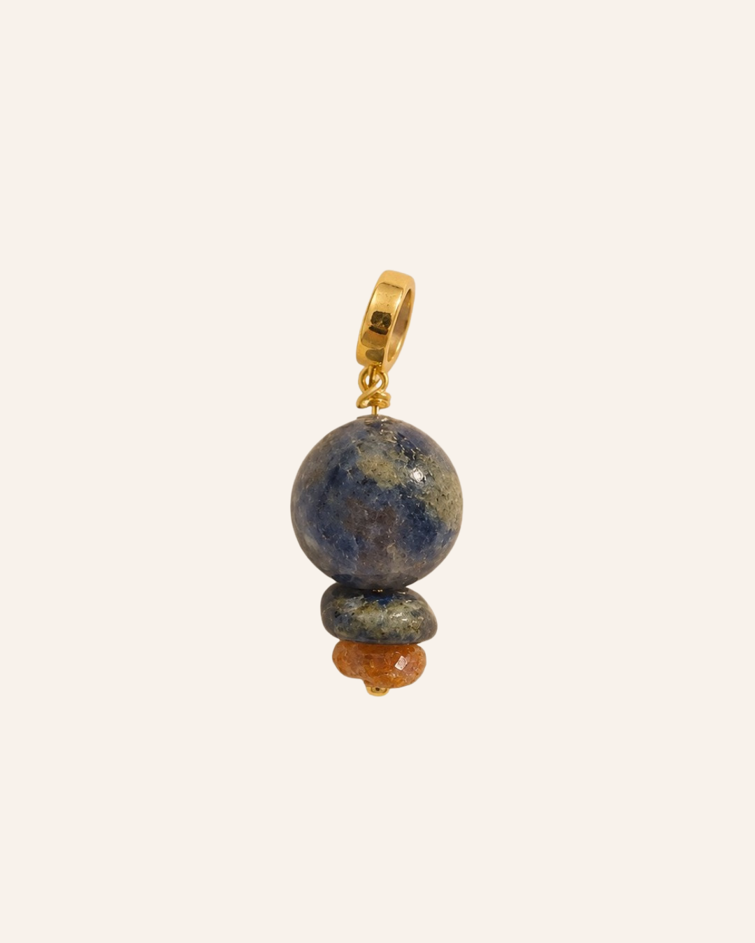 A beaded drop earring charm featuring a large round lapis lazuli stone, a smaller dark stone, and a tiny orange bead, suspended from a gold hoop on a light beige background.