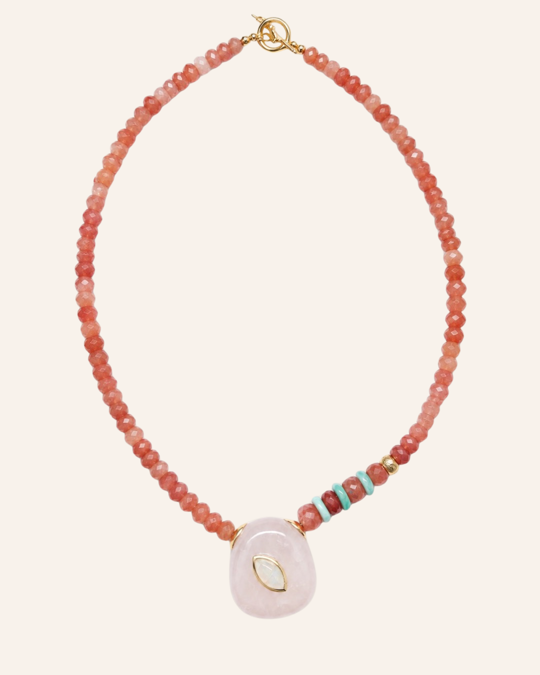 A beaded necklace featuring a loop of small coral-pink and peach beads, a small cluster of turquoise and red beads, and a large pale pink stone pendant with a gold leaf detail, shown on a light cream background.