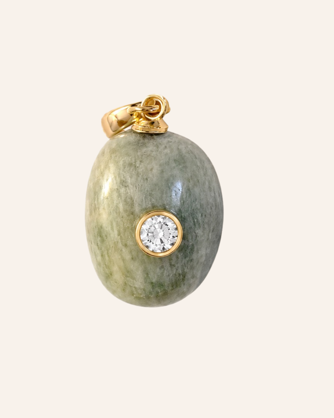 An oval pendant featuring a polished green stone with natural marbling, accented by a gold bail at the top and a bezel-set round clear gemstone near the center, shown against a solid light beige background.