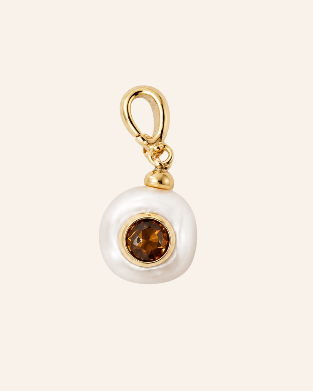 A gold charm pendant featuring a white freshwater pearl with a pink tourmaline  gemstone, set against a solid pale pink background.