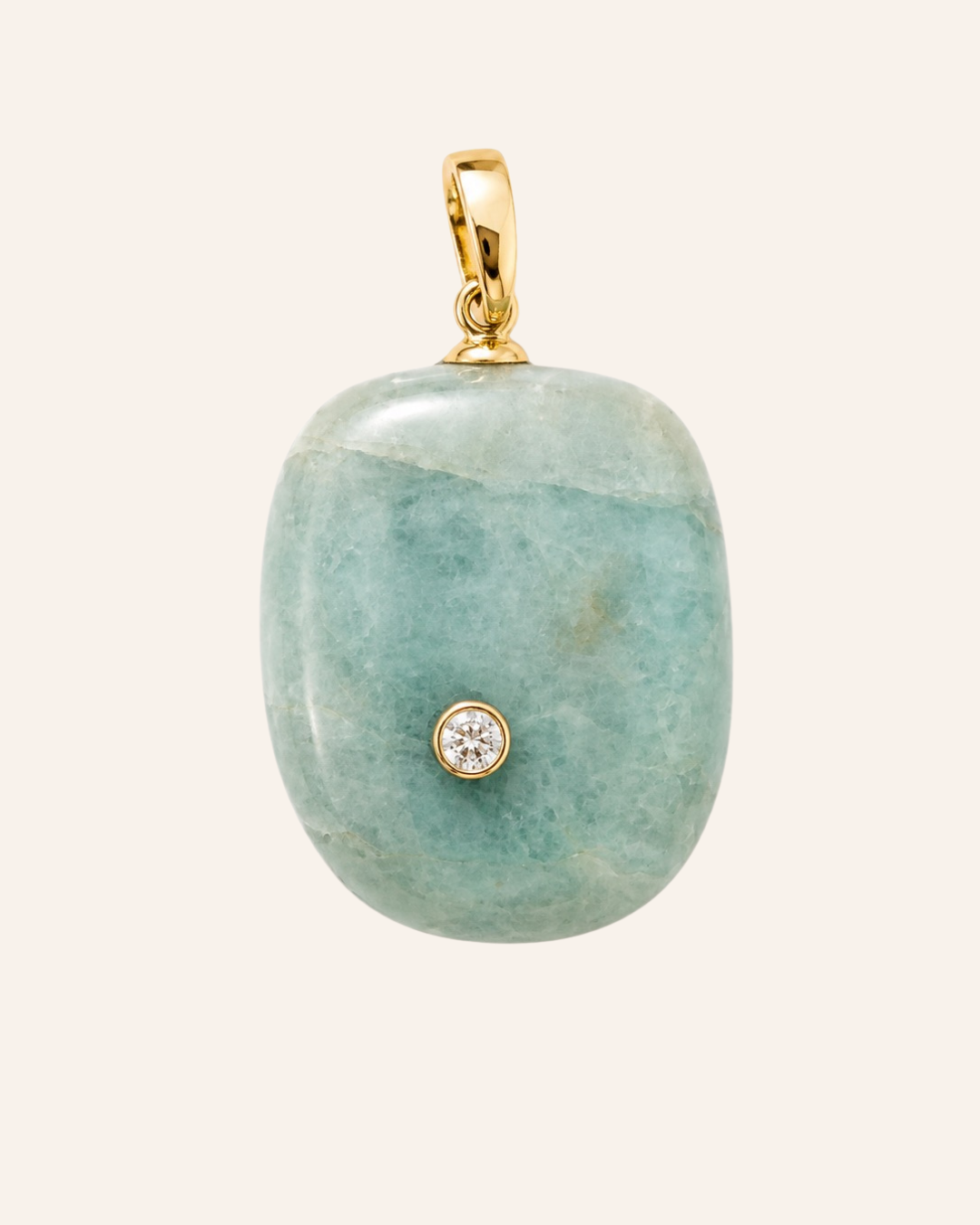 A polished light green stone pendant with a small gold bezel-set clear gemstone, suspended from a gold bail, shown against a solid pale beige background.